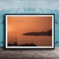 a serene sunset over a body of water, with a small island visible in the distance.