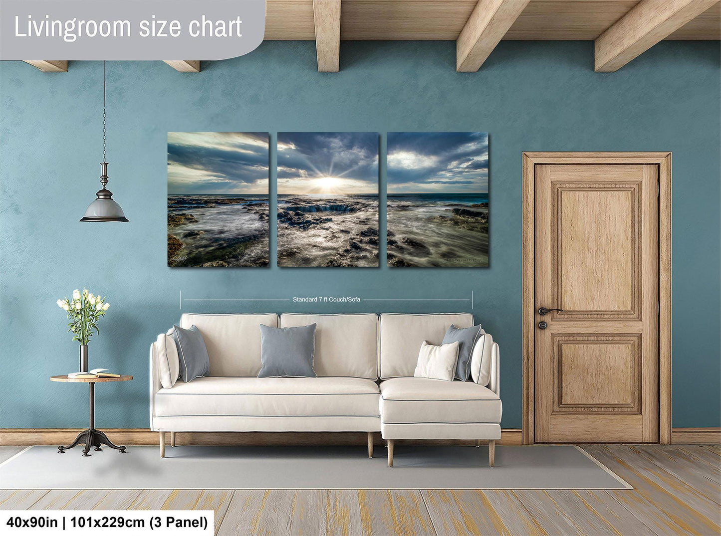 The image is a living room with a large, three-panel landscape painting hanging on the wall. The painting depicts a serene beach scene with waves crashing against the shore. The room is furnished with a white sofa and a wooden door, creating a cozy and inviting atmosphere.