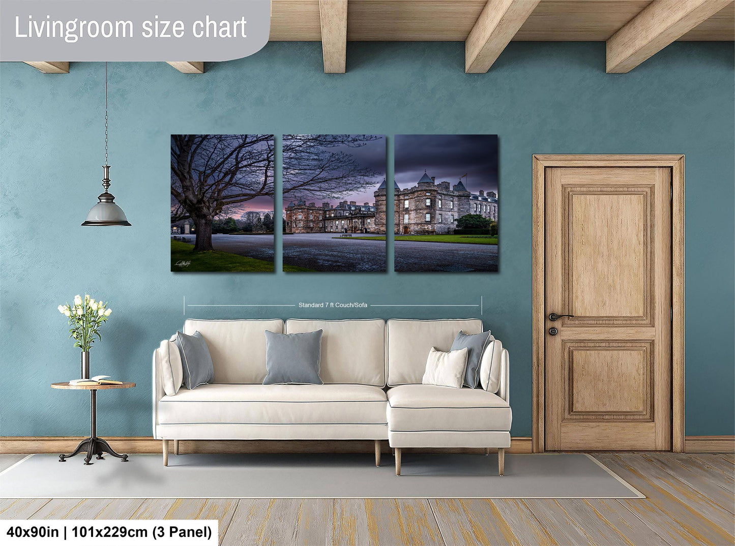 The image is a living room with a large white sofa, a wooden door, and a painting of a building on the wall.