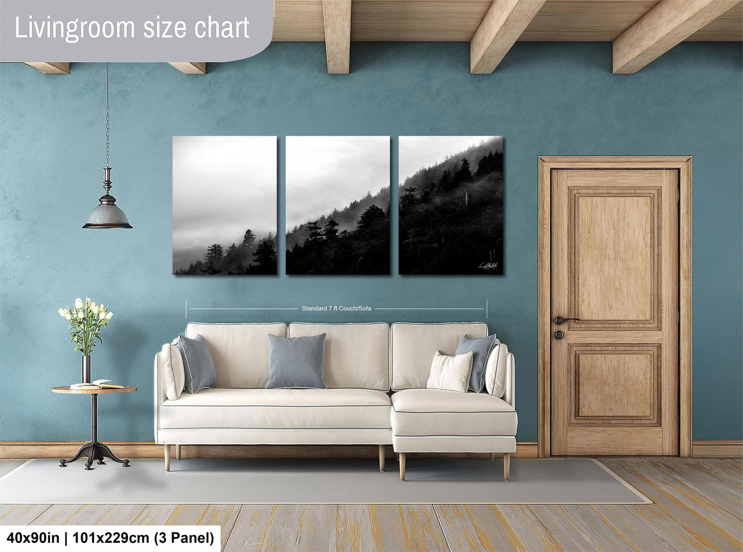 The image is a living room with a white sofa, a wooden door, and a wall with a large painting depicting a forest scene.