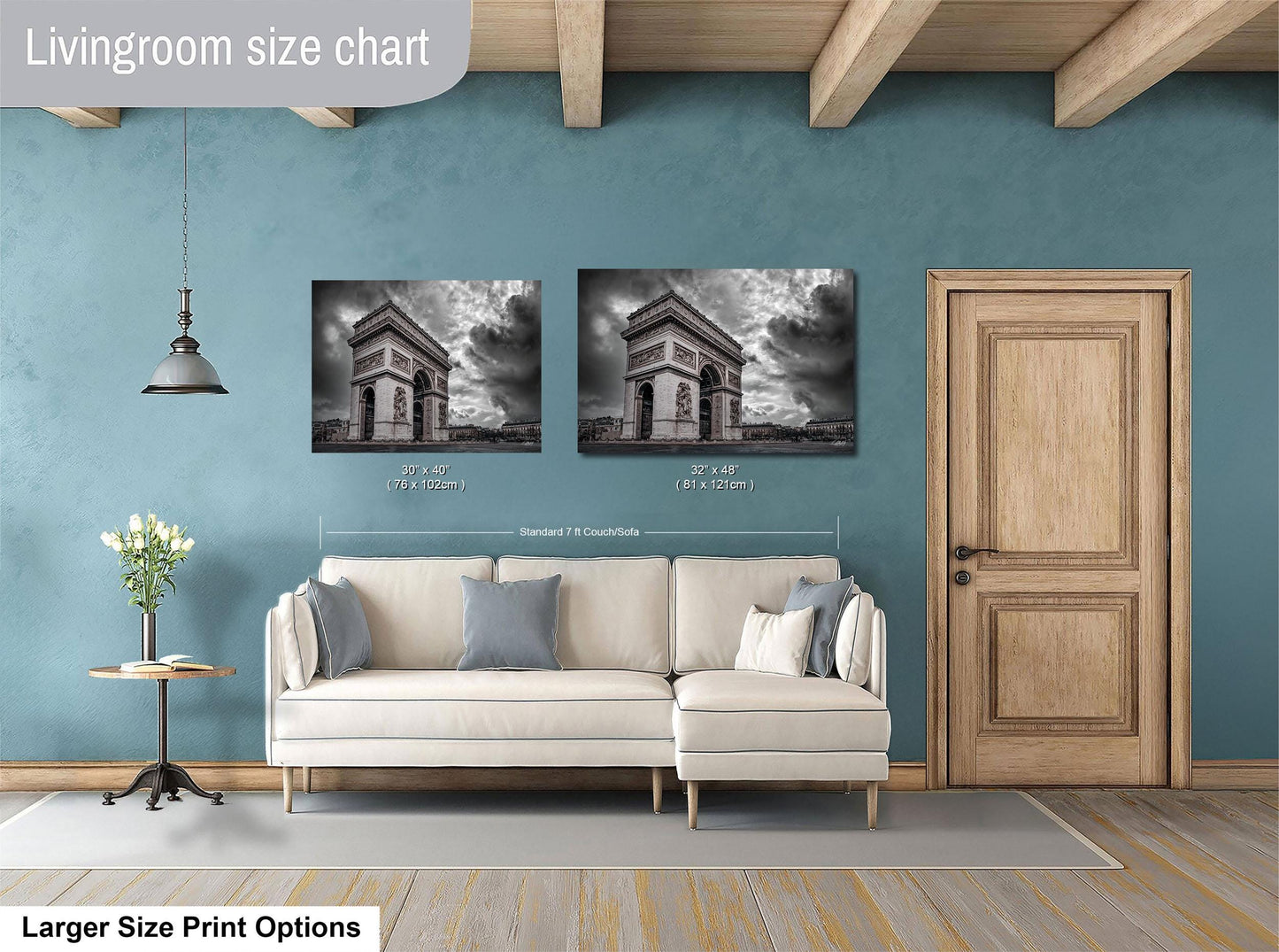 a living room with a white sofa, a wooden door, and two framed photographs of the Arc de Triomphe in Paris. The living room has a blue wall and a wooden floor.