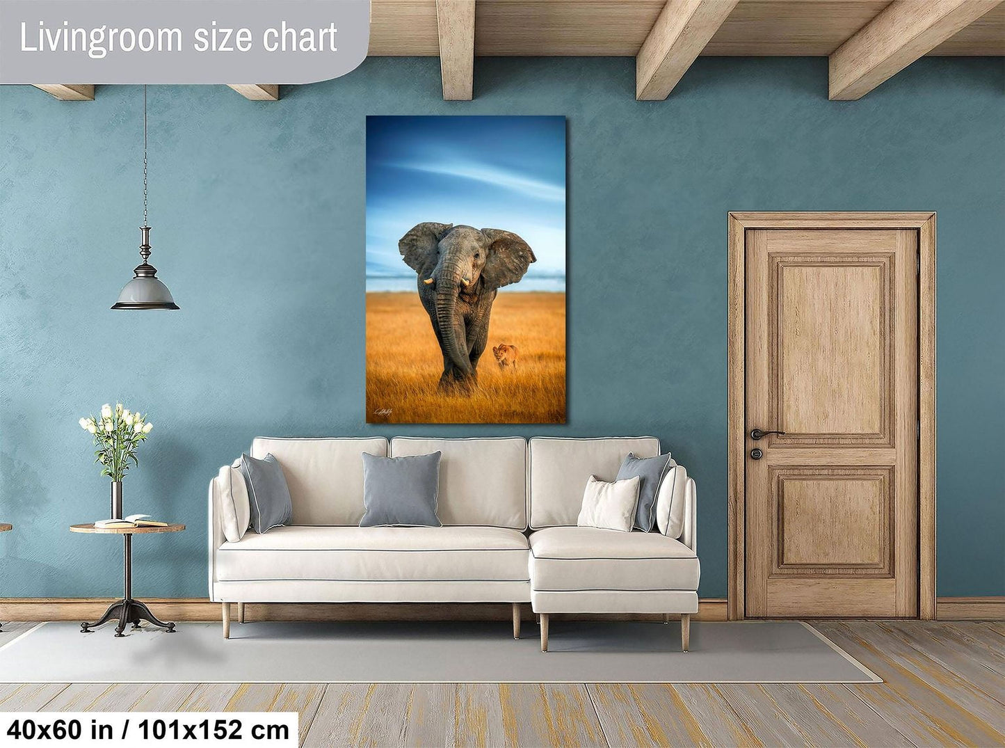 a living room with a large painting of an elephant on the wall, a white sofa, a wooden door, and a small table with a vase of flowers.