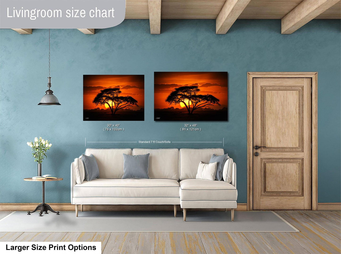 a living room with a white sofa and a wooden door. Above the sofa, there are two framed pictures of a sunset, with one picture being larger than the other. The living room has a blue wall and a wooden ceiling.