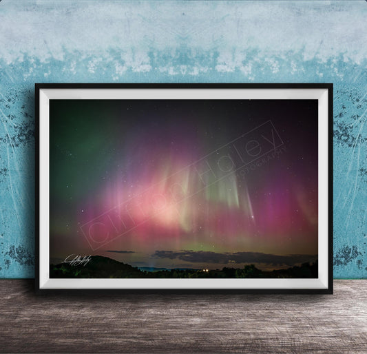 The image is a framed photograph of a night sky with the aurora borealis, or northern lights, visible.