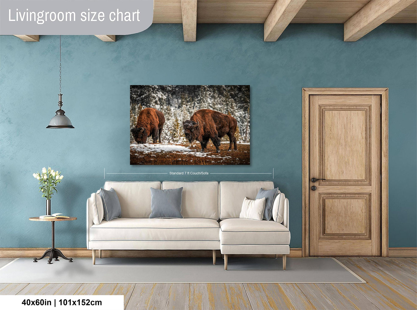 a living room with a large painting of two bison in the snow hanging on the wall. The painting is framed and measures 40 inches by 101.5 centimeters. The room has a white sofa and a wooden door, creating a cozy and rustic atmosphere.