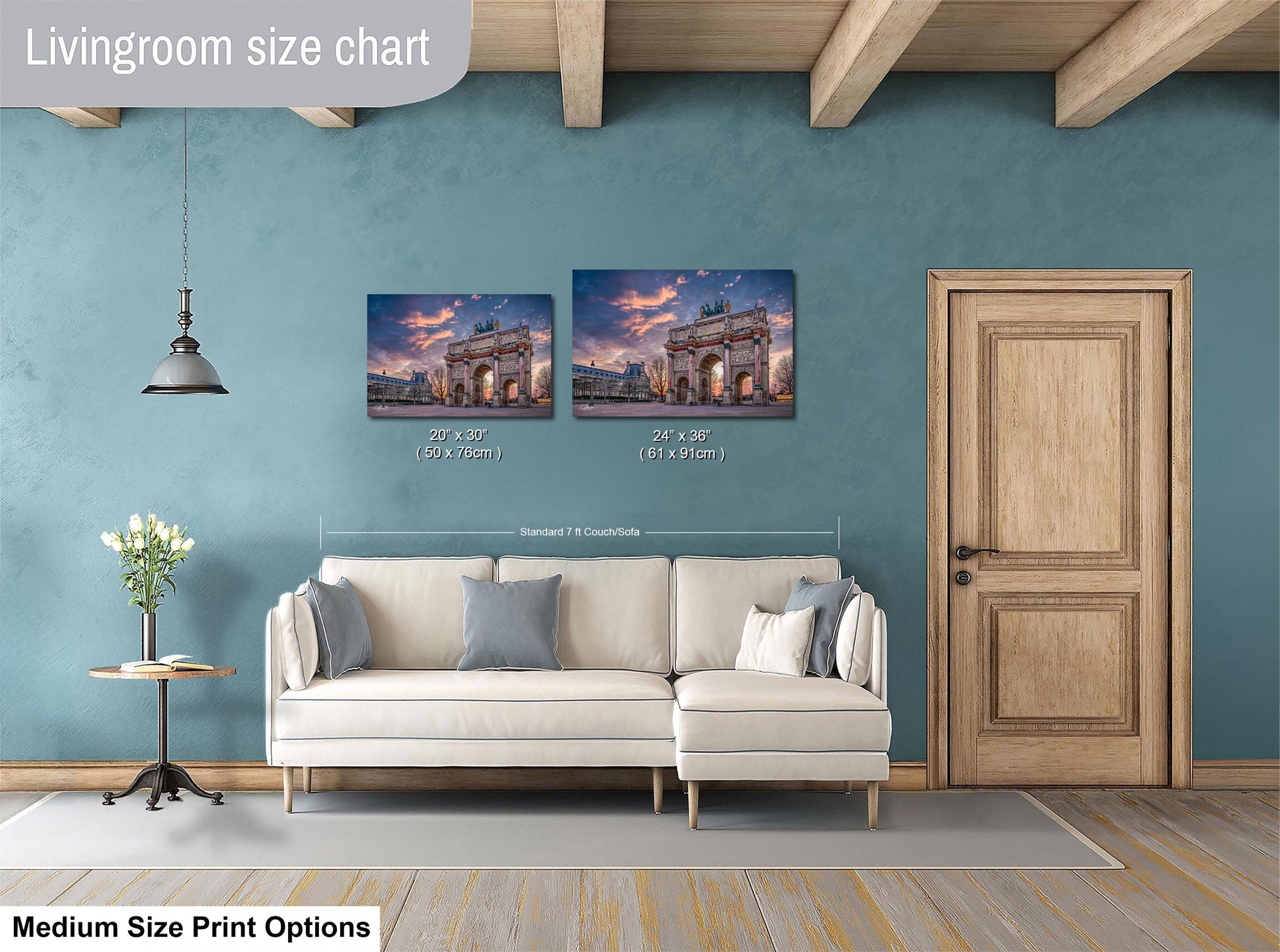 a living room with a white sofa and a wooden door. Above the sofa, there are two framed pictures of a building, likely a monument, hanging on the wall. The wall has a blue color, and there is a lamp hanging from the ceiling. The living room appears to be well-decorated and spacious.