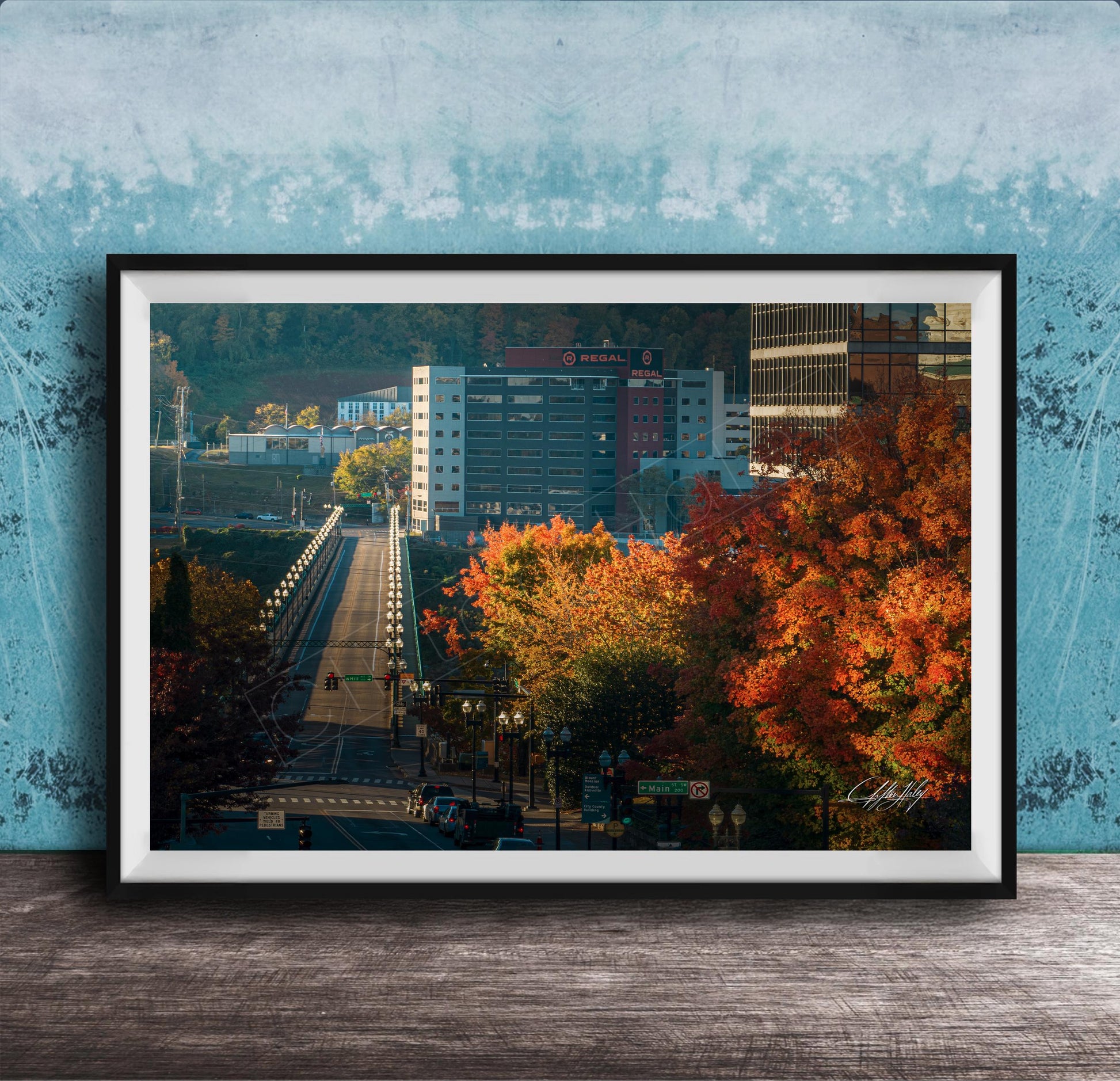 a cityscape with a bridge, buildings, and trees with autumn foliage.