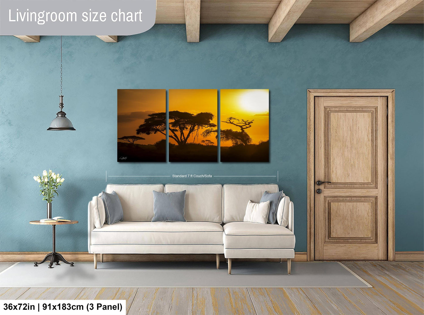 The image is a living room with a large wall art piece depicting a sunset over a landscape. The art piece is divided into three panels, with the top and bottom panels showing a silhouette of trees and the middle panel showing the sun setting over the landscape. The living room has a white sofa and a wooden door, and the wall art is approximately 36 inches wide and 91 inches tall.