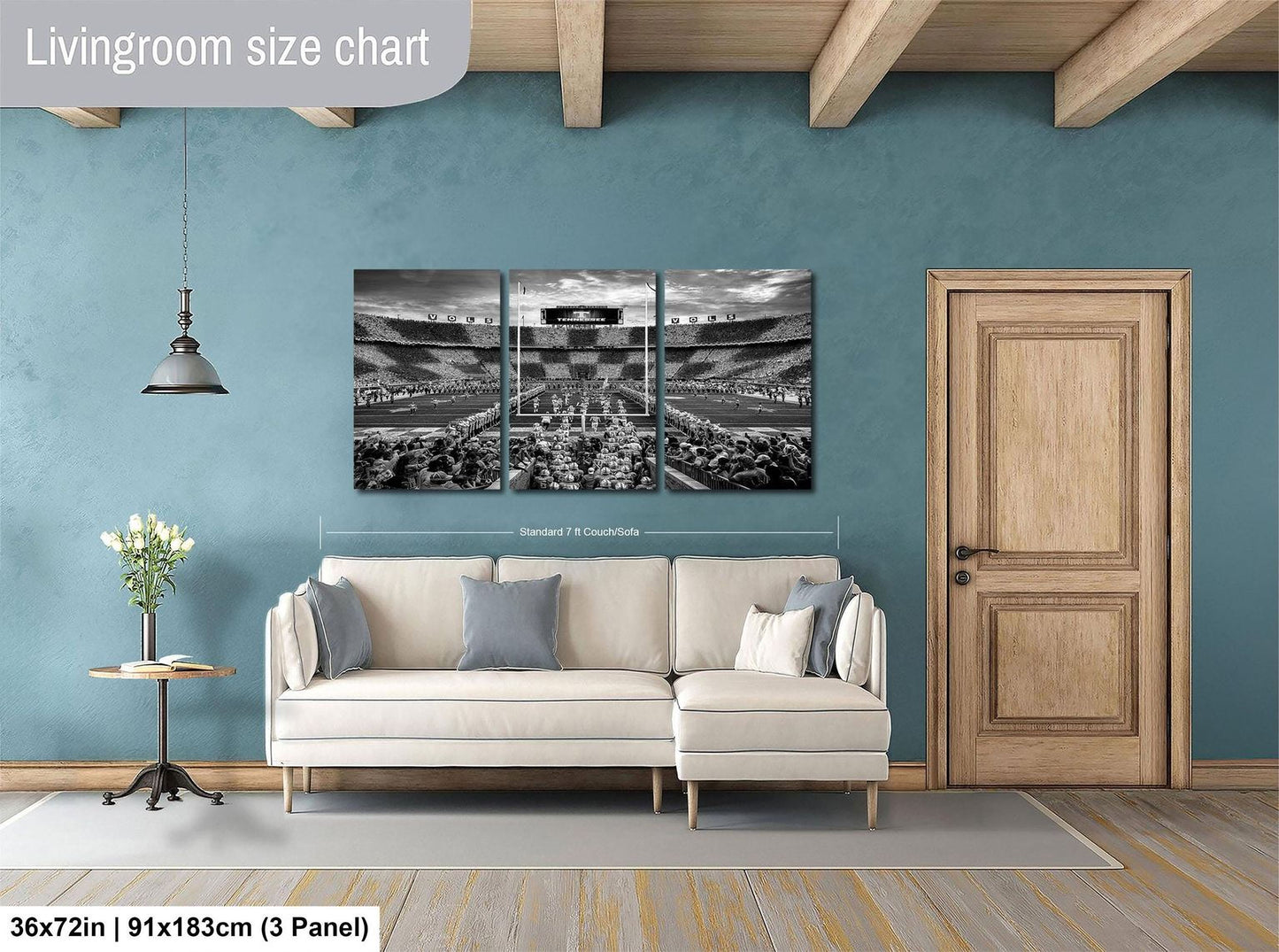 The image is a living room with a large wall-mounted painting depicting a stadium scene. The painting is divided into three panels, with the largest panel covering the entire wall. The room has a white sofa, a wooden door, and a small table with a vase of flowers. The wall is painted in a light blue color, and the floor is made of wood. The painting is described as a "Livingroom size chart" and is shown to be 36 square feet in size.