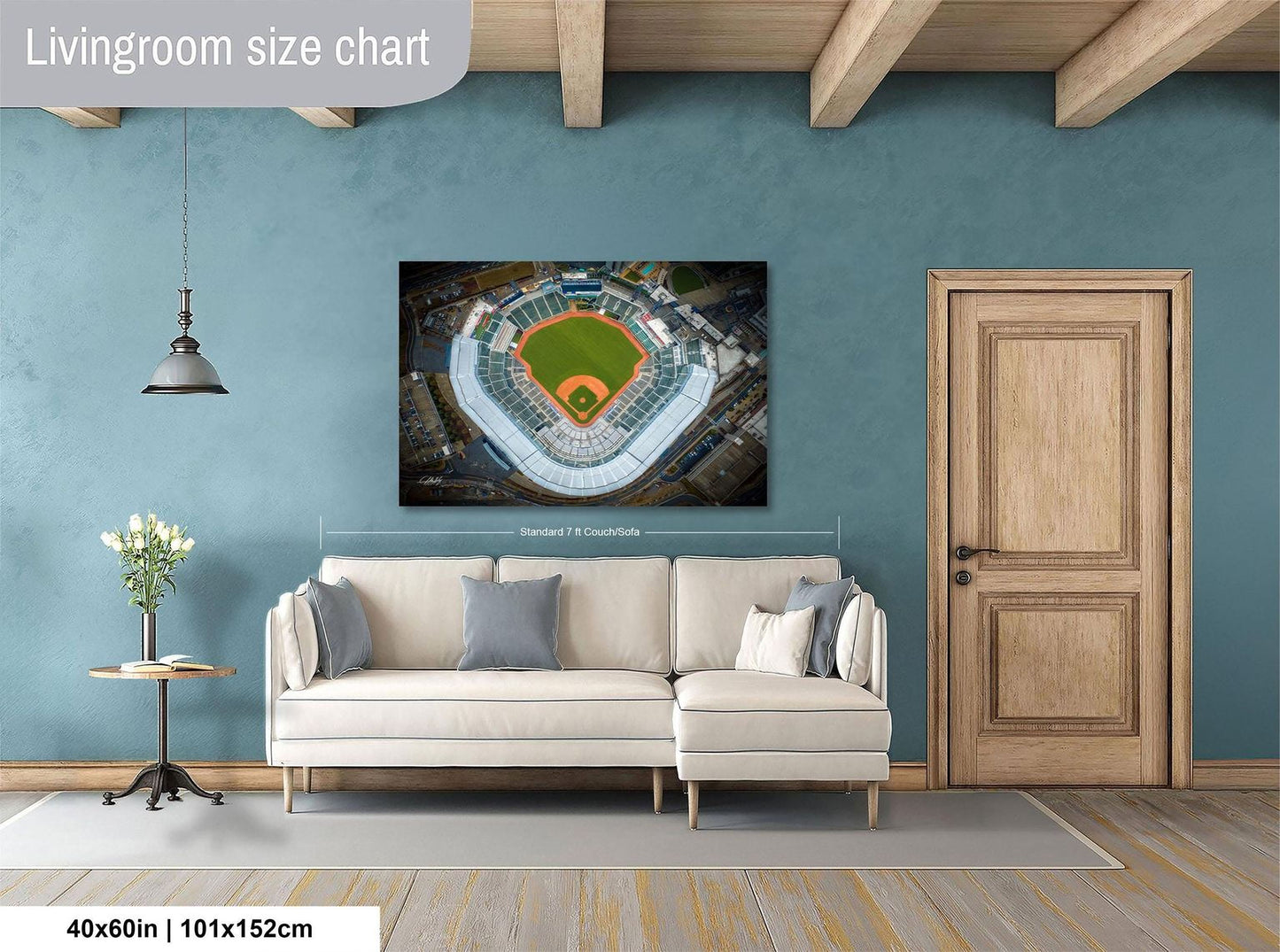 a living room with a large wall-mounted poster of a baseball stadium, a white sofa, a wooden door, and a small table with a vase of flowers.