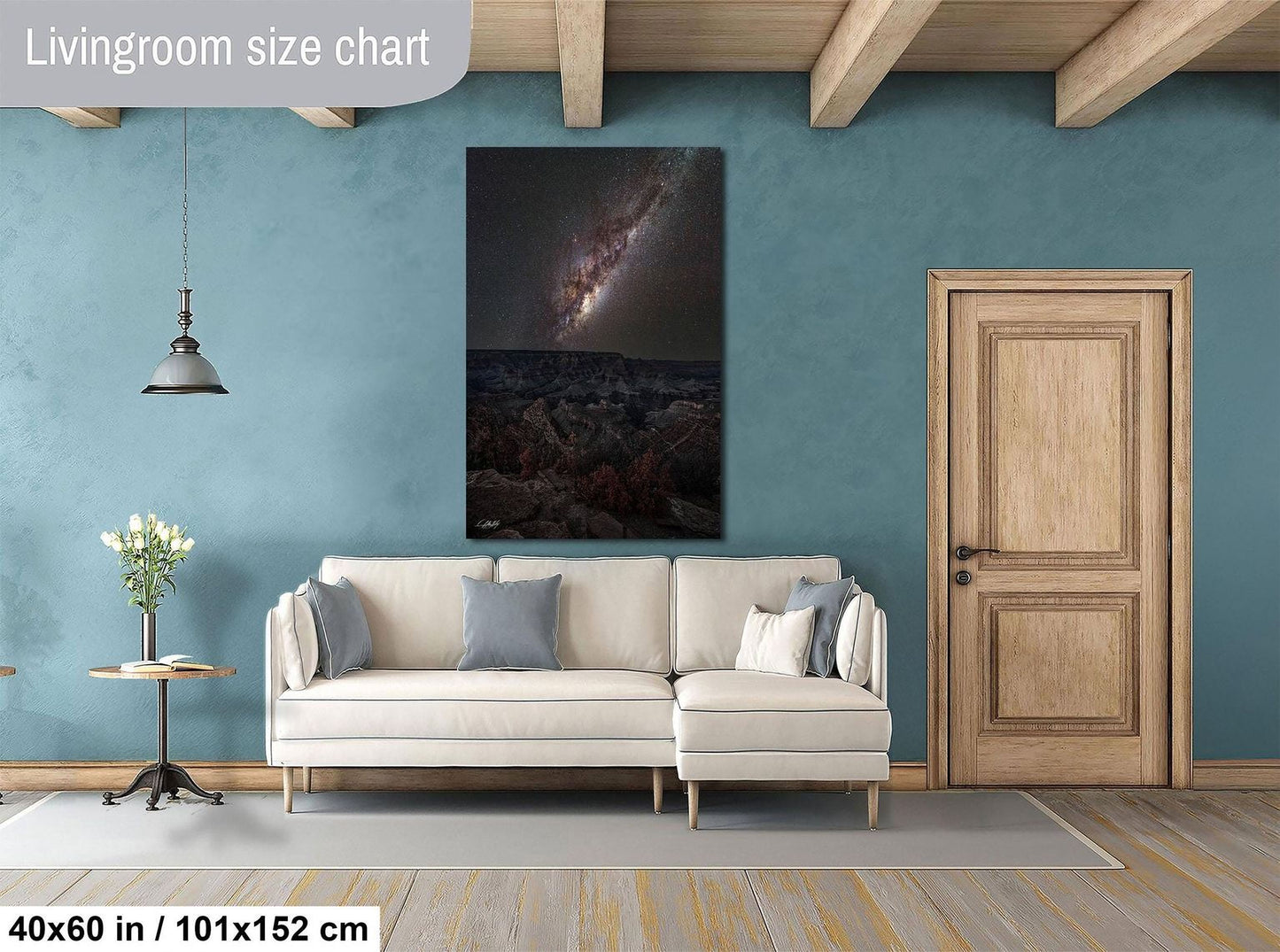 a living room with a large white sofa, a wooden door, and a painting of a galaxy hanging on the wall.