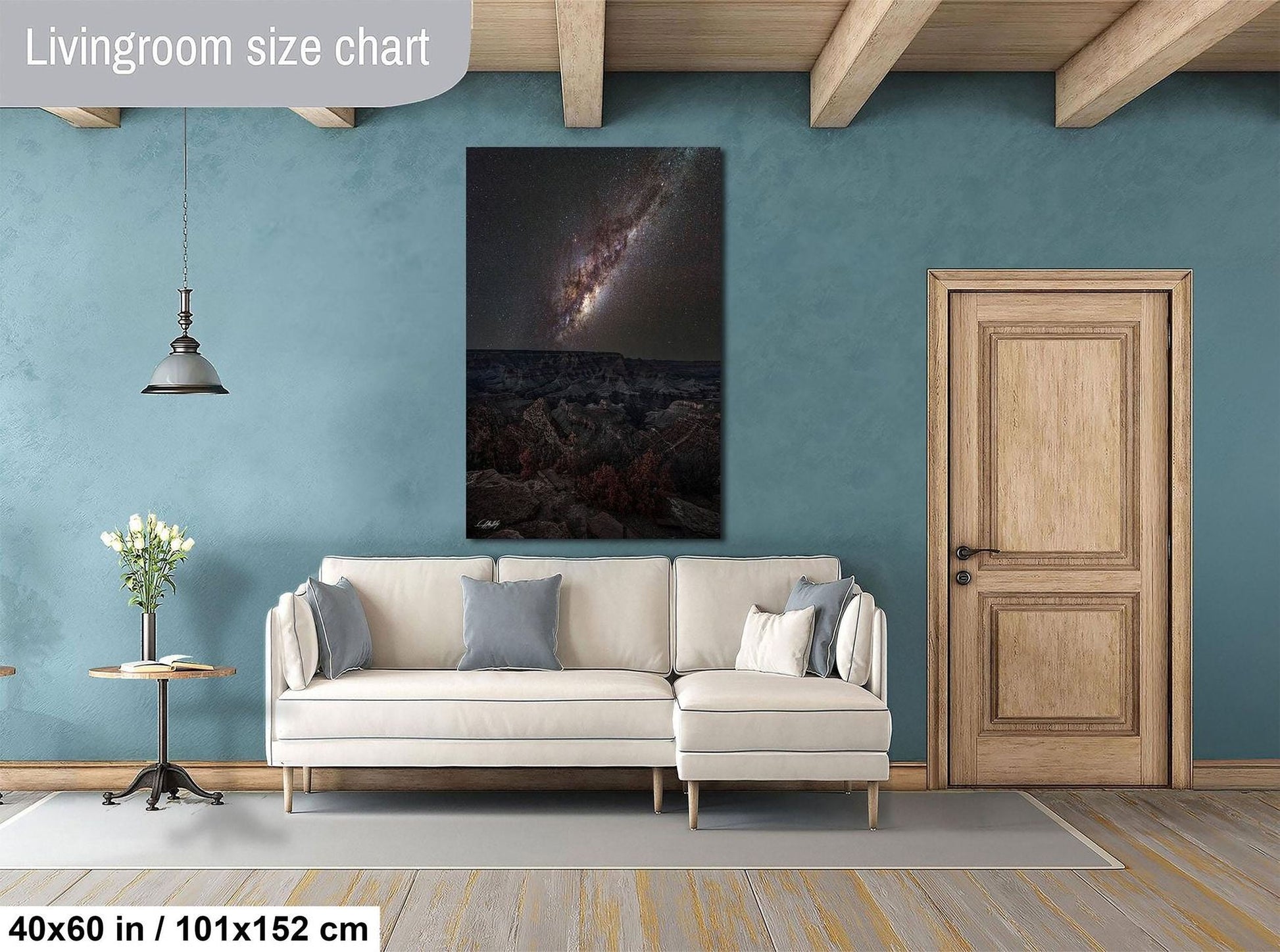 a living room with a large white sofa, a wooden door, and a painting of a galaxy hanging on the wall.