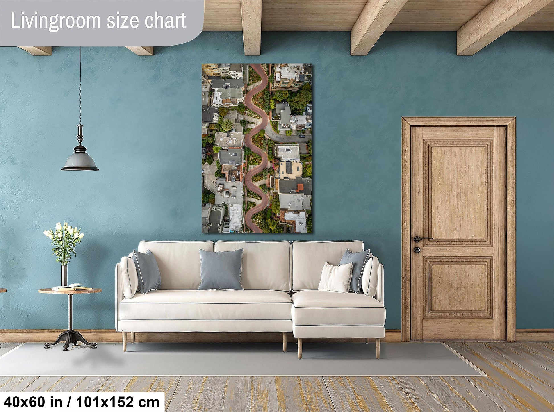 a living room with a large white sofa, a wooden door, and a painting of a cityscape hanging on the wall.