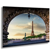 the Eiffel Tower, a famous landmark in Paris, France, captured from a unique perspective under an archway. The tower is visible in the background, with a clear blue sky and a few clouds above. The scene is framed by a stone archway, adding a sense of grandeur to the image.