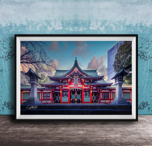 A framed photograph of a traditional Japanese temple with a red roof and white walls, set against a blue sky with clouds.
