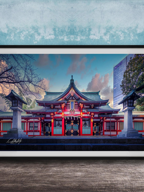 A framed photograph of a traditional Japanese temple with a red roof and white walls, set against a blue sky with clouds.
