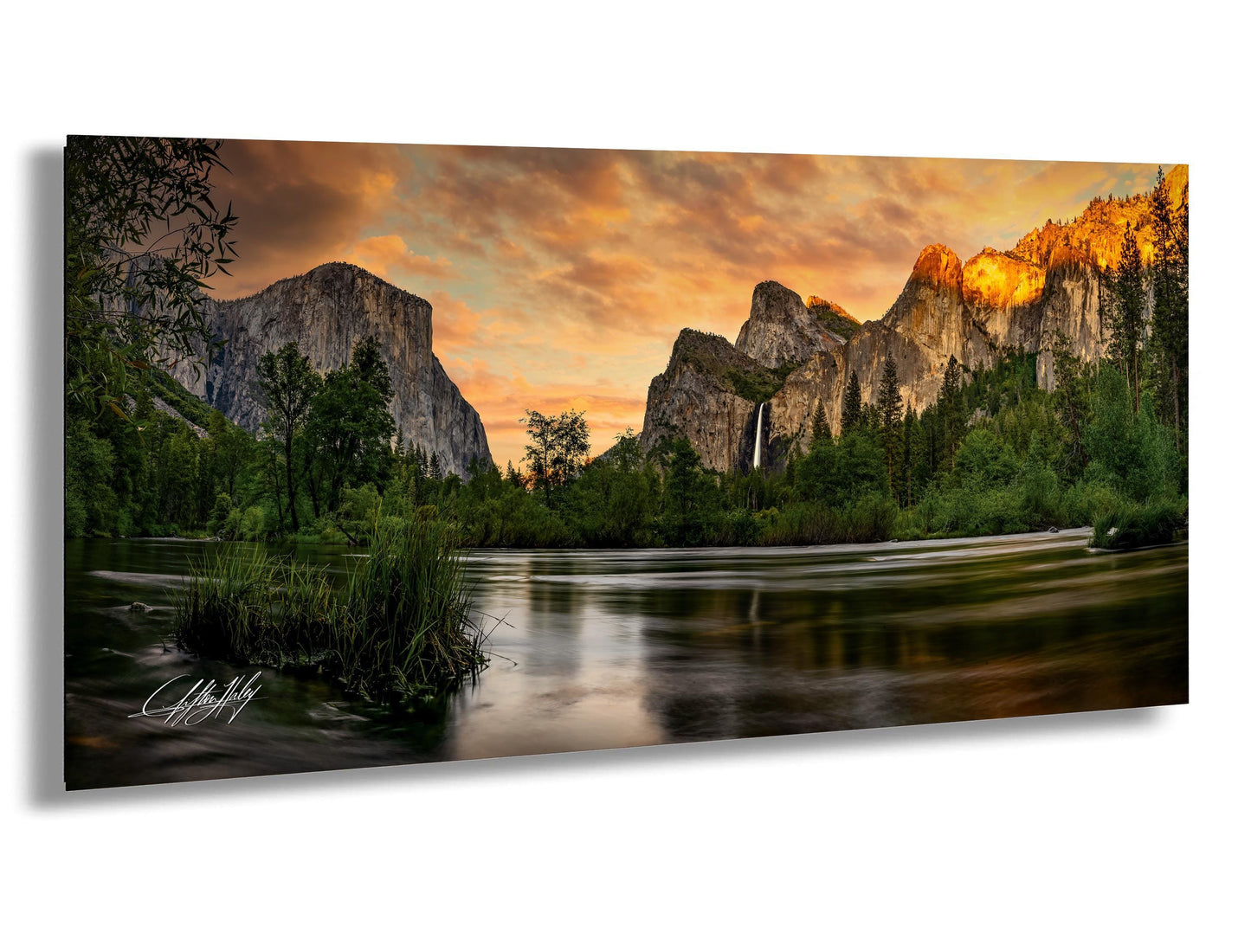 a serene landscape with a calm river reflecting the vibrant colors of the sky, surrounded by towering mountains and lush greenery.