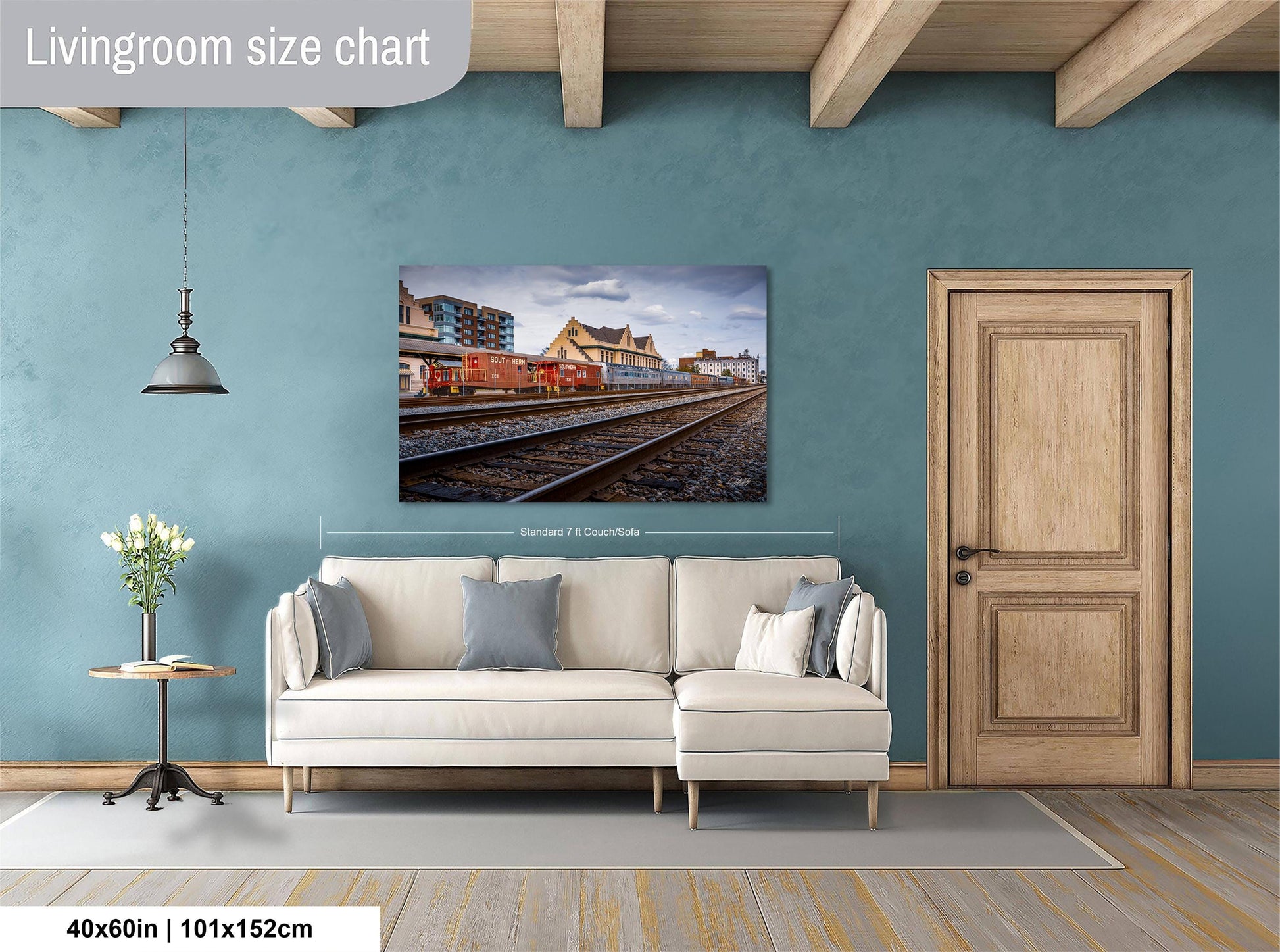 a living room with a large white sofa, a wooden door, and a painting of a train on the wall.