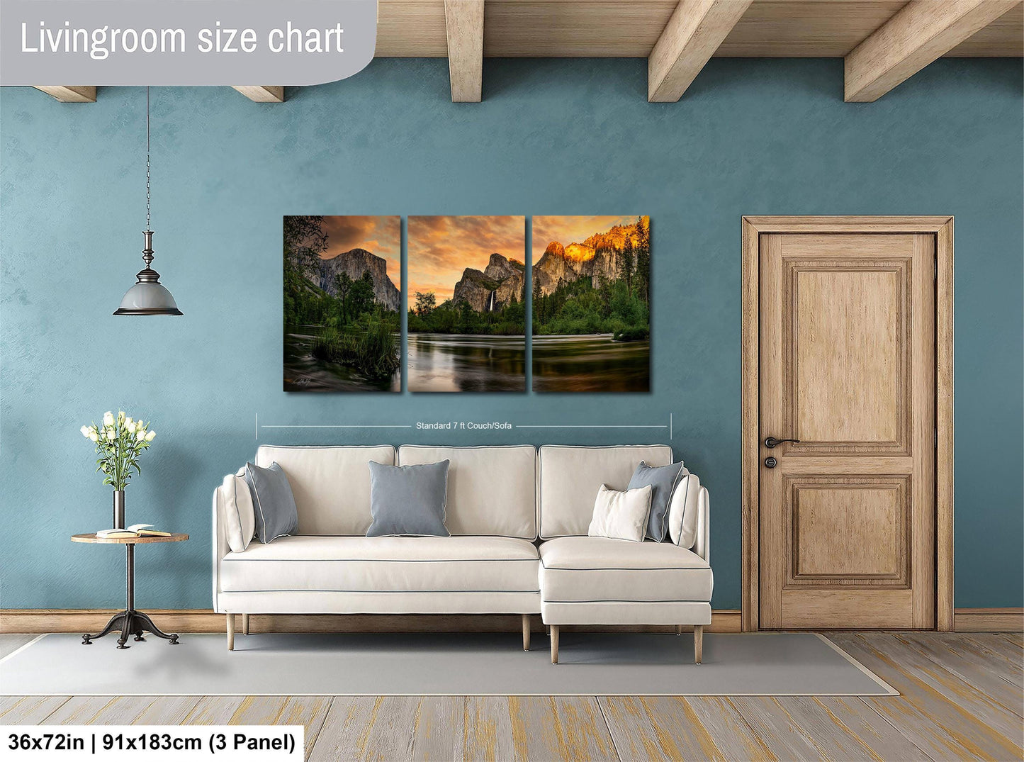 The image is a living room with a large wall art piece depicting a scenic landscape with mountains and a lake. The art piece is divided into three panels, each showcasing different aspects of the landscape. The living room has a white sofa and a wooden door, creating a cozy and inviting atmosphere.