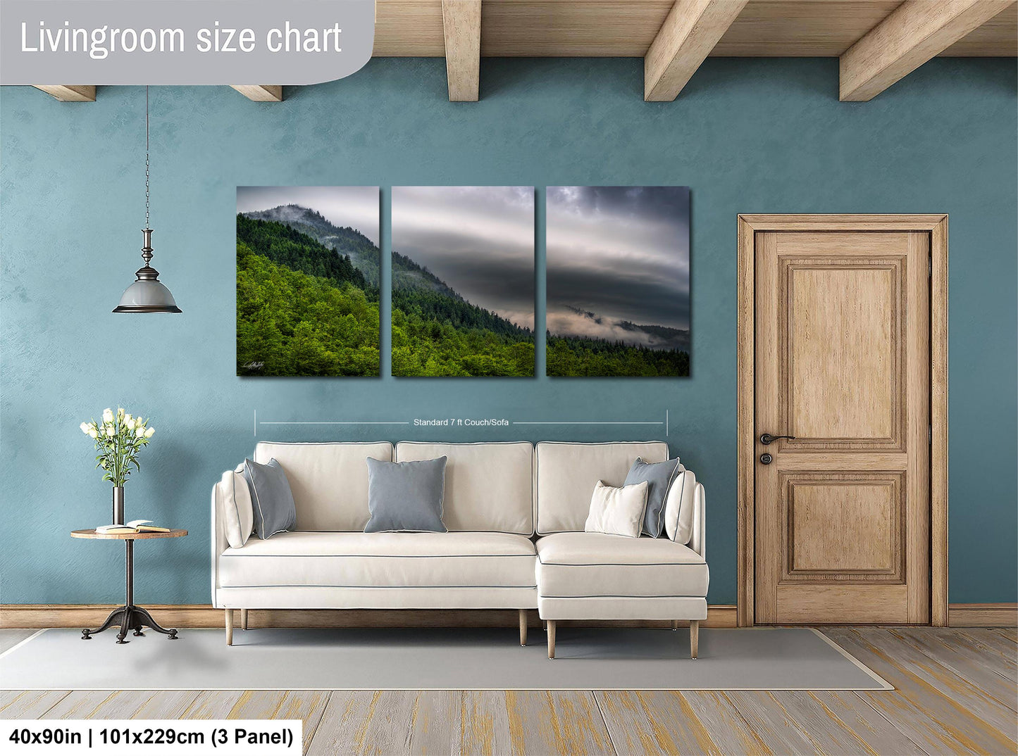 The image is a living room with a large white sofa, a wooden door, and a painting of a mountain landscape hanging on the wall.