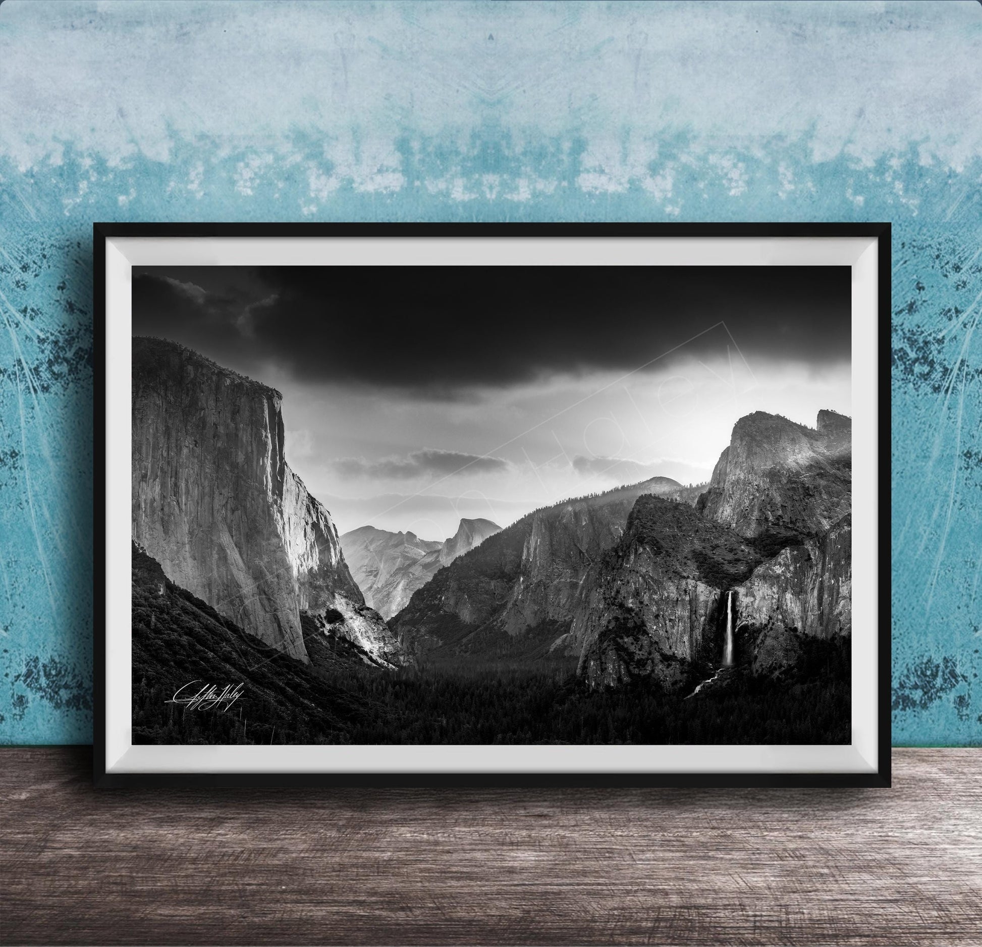 A black and white photograph of a mountainous landscape, with dramatic clouds and a waterfall in the foreground.