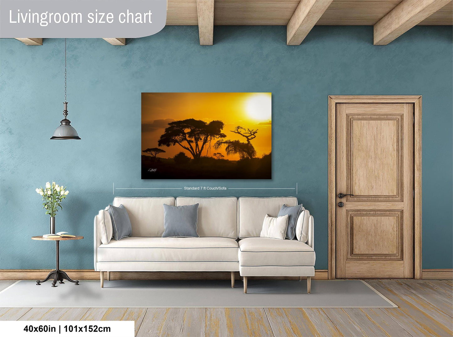 a living room with a large painting of a sunset landscape hanging on the wall. The painting is framed in a white frame and measures 40 inches by 101.5 centimeters. The room has a white sofa and a wooden door, creating a cozy and inviting atmosphere.