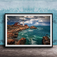 A framed photograph of a lighthouse on a rocky coastline, with the ocean and cloudy sky visible in the background.