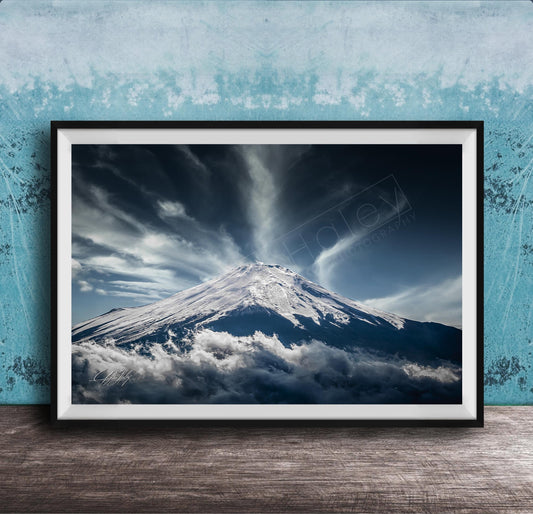 A framed photograph of a snow-capped mountain peak, with dramatic clouds and a dramatic sky in the background.