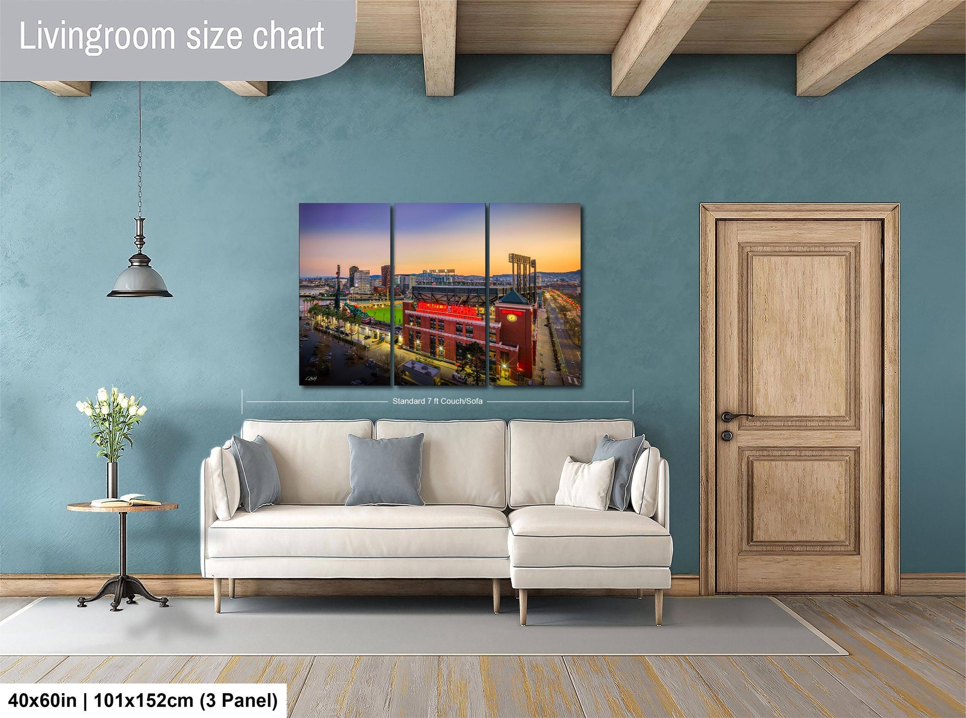 The image is a living room with a large white sofa, a wooden door, and a painting of a cityscape hanging on the wall.