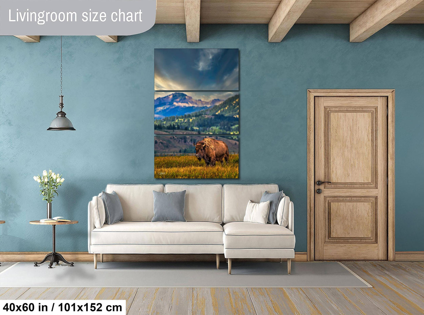 a living room with a large painting of a bear in a grassy field hanging on the wall. The painting is framed in a wooden frame and is approximately 40 inches wide and 101.5 inches tall. The room has a white sofa and a wooden door, creating a cozy and inviting atmosphere.