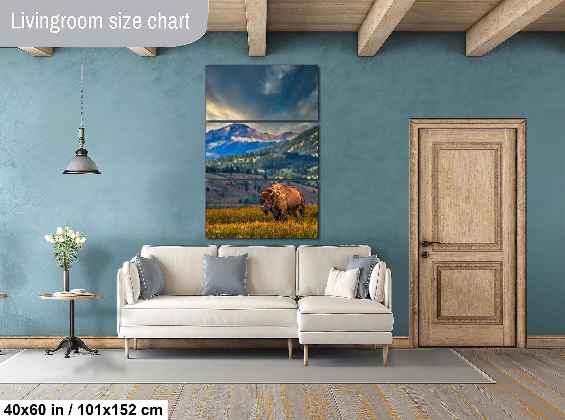 a living room with a large painting of a bear in a grassy field hanging on the wall. The painting is framed in a wooden frame and is approximately 40 inches wide and 101.5 inches tall. The room has a white sofa and a wooden door, creating a cozy and inviting atmosphere.