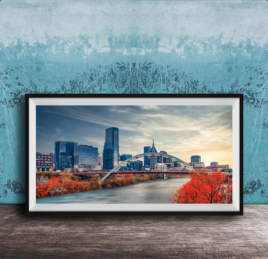 a framed photograph of a city skyline with a bridge and trees in the foreground.