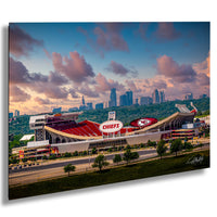 A large stadium with a prominent Kansas City Chiefs logo, surrounded by a city skyline and a colorful sunset sky.