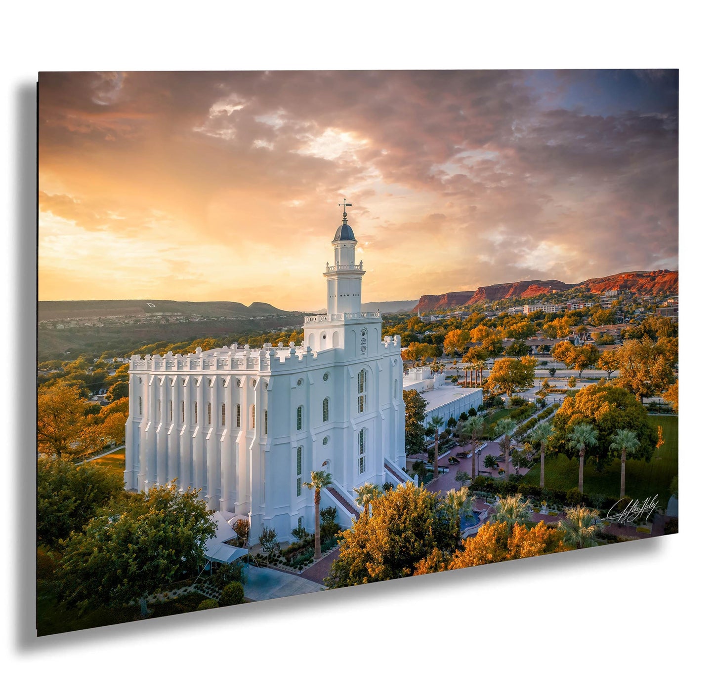 a large white temple with a tall tower, surrounded by trees and mountains, with a colorful sunset sky in the background.