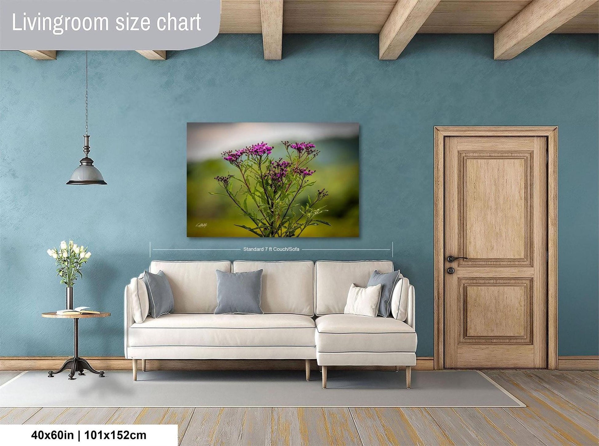 a living room with a white sofa, a wooden door, and a painting of purple flowers hanging on the wall.