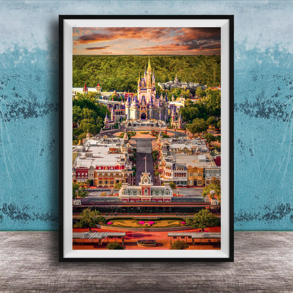 A framed aerial view of a colorful and whimsical theme park, with a castle-like structure in the background and various buildings and attractions in the foreground.