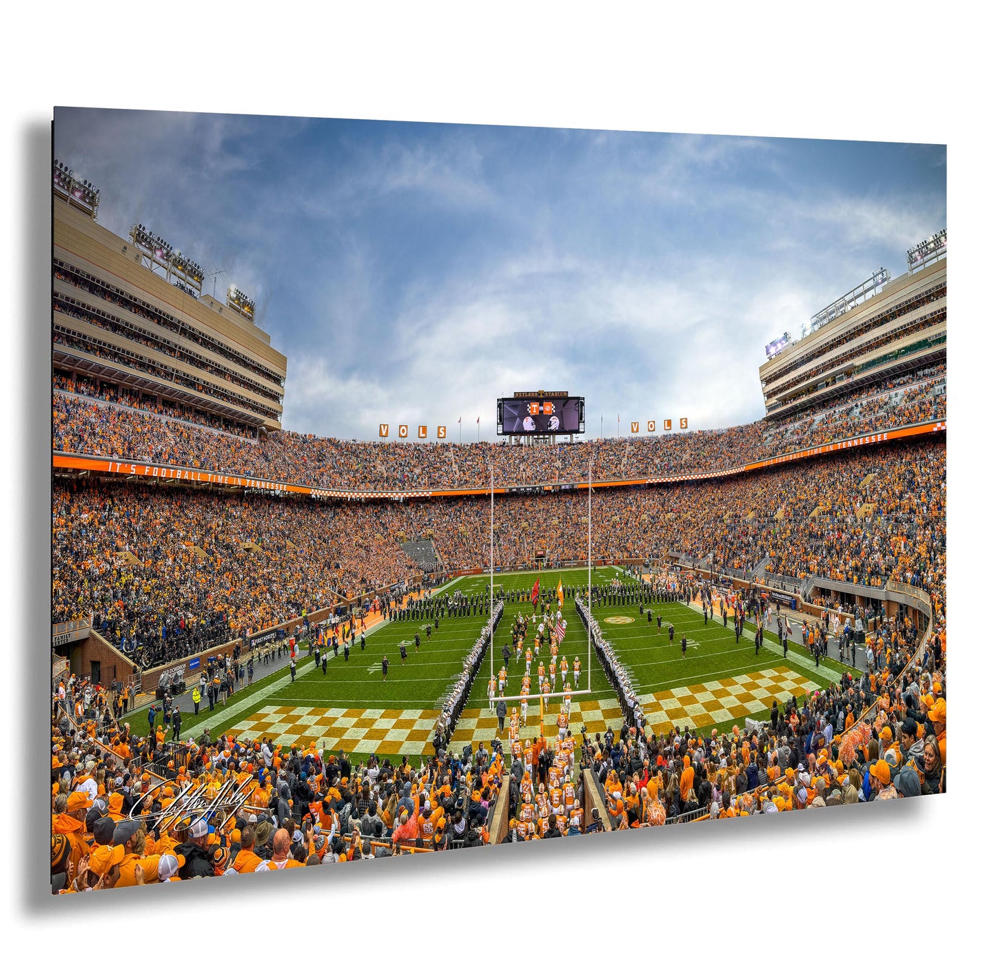 A crowded football stadium with a large audience, featuring a football field, cheerleaders, and a large scoreboard.