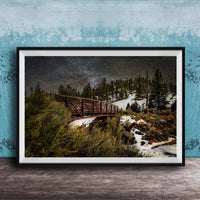 A framed photograph depicting a wooden bridge crossing a snowy mountain landscape at night, with a starry sky overhead.