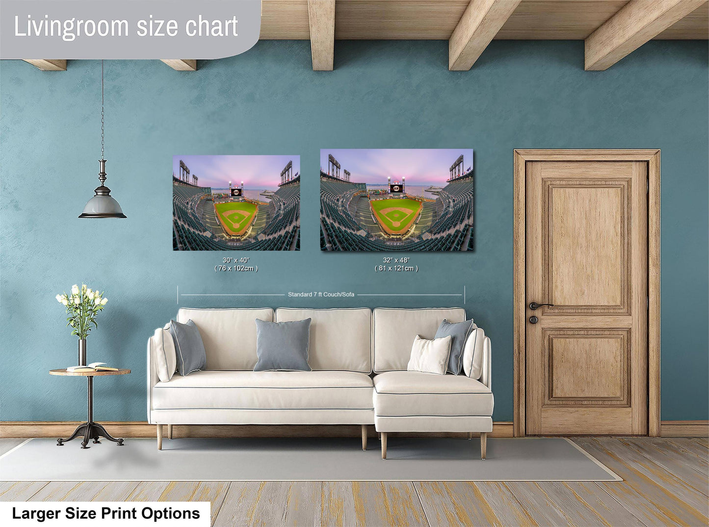 a living room with a white sofa and a wooden door. Above the sofa, there are two framed pictures of a baseball stadium, one larger than the other. The larger picture is labeled as "Larger Size Print Options" and the smaller picture is labeled as "Standard 7x7 inches".
