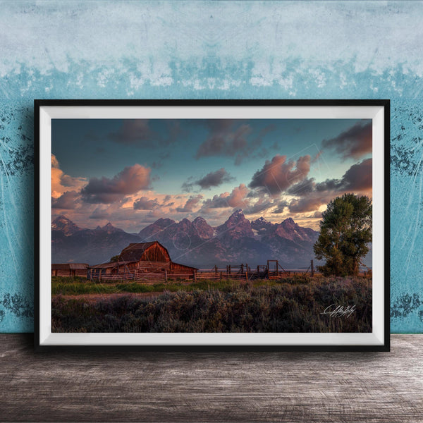 a rustic wooden barn nestled in a grassy field, with majestic mountains in the background under a vibrant sky.