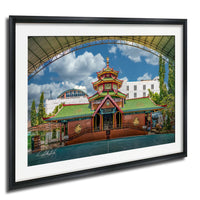 A framed photograph of a traditional Chinese temple with a green roof and red walls, surrounded by trees and a clear blue sky.