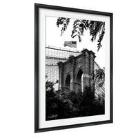 A black and white photograph of the Brooklyn Bridge, with the American flag flying above the bridge.