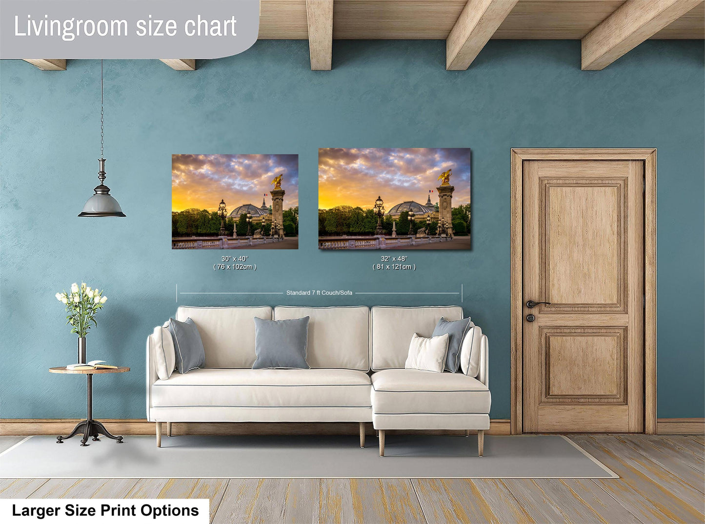 a living room with a white sofa and a wooden door. Above the sofa, there are two framed pictures of a cityscape, and the wall has a blue color. The living room appears to be well-lit and decorated.