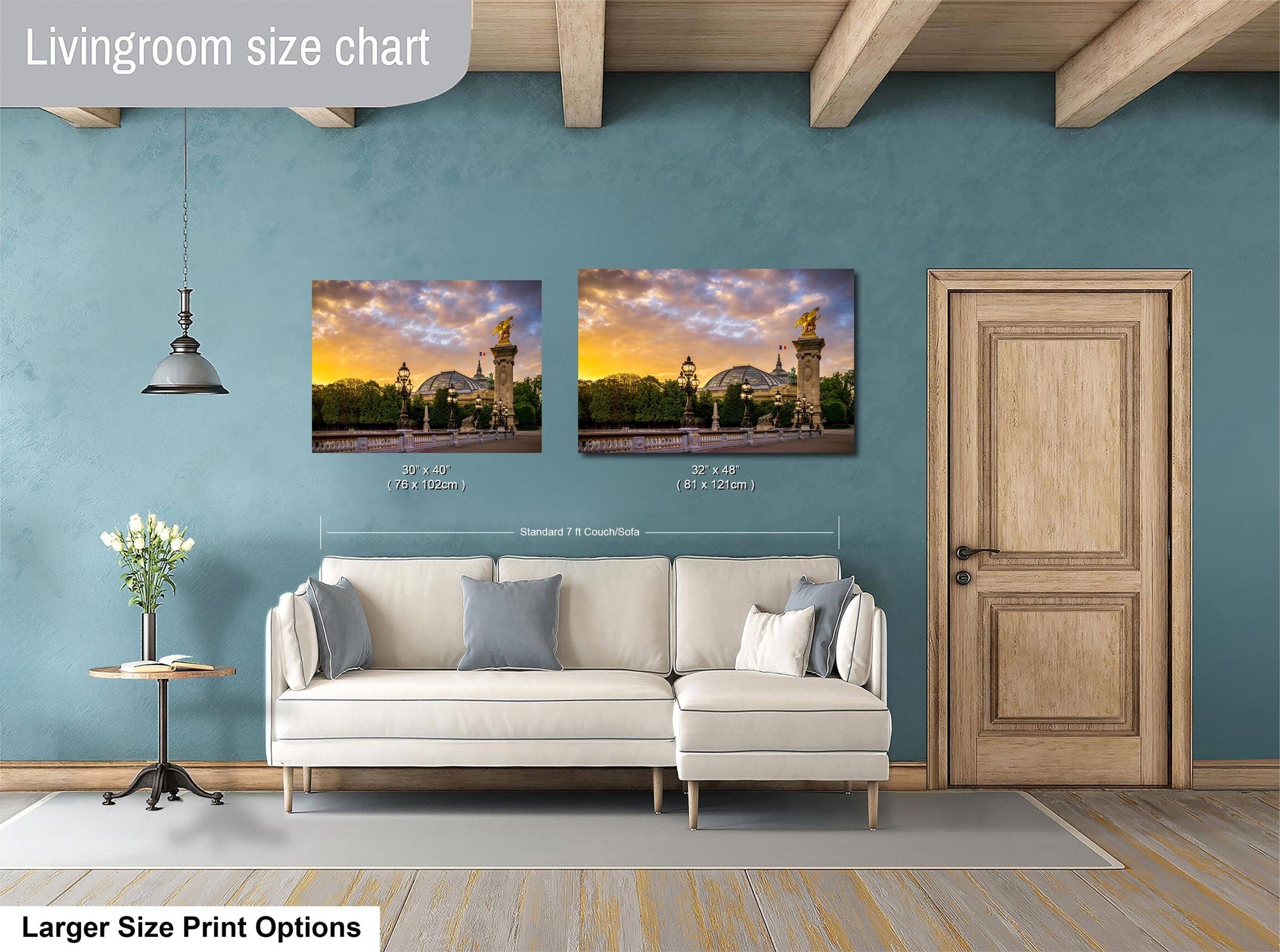 a living room with a white sofa and a wooden door. Above the sofa, there are two framed pictures of a cityscape, and the wall has a blue color. The living room appears to be well-lit and decorated.