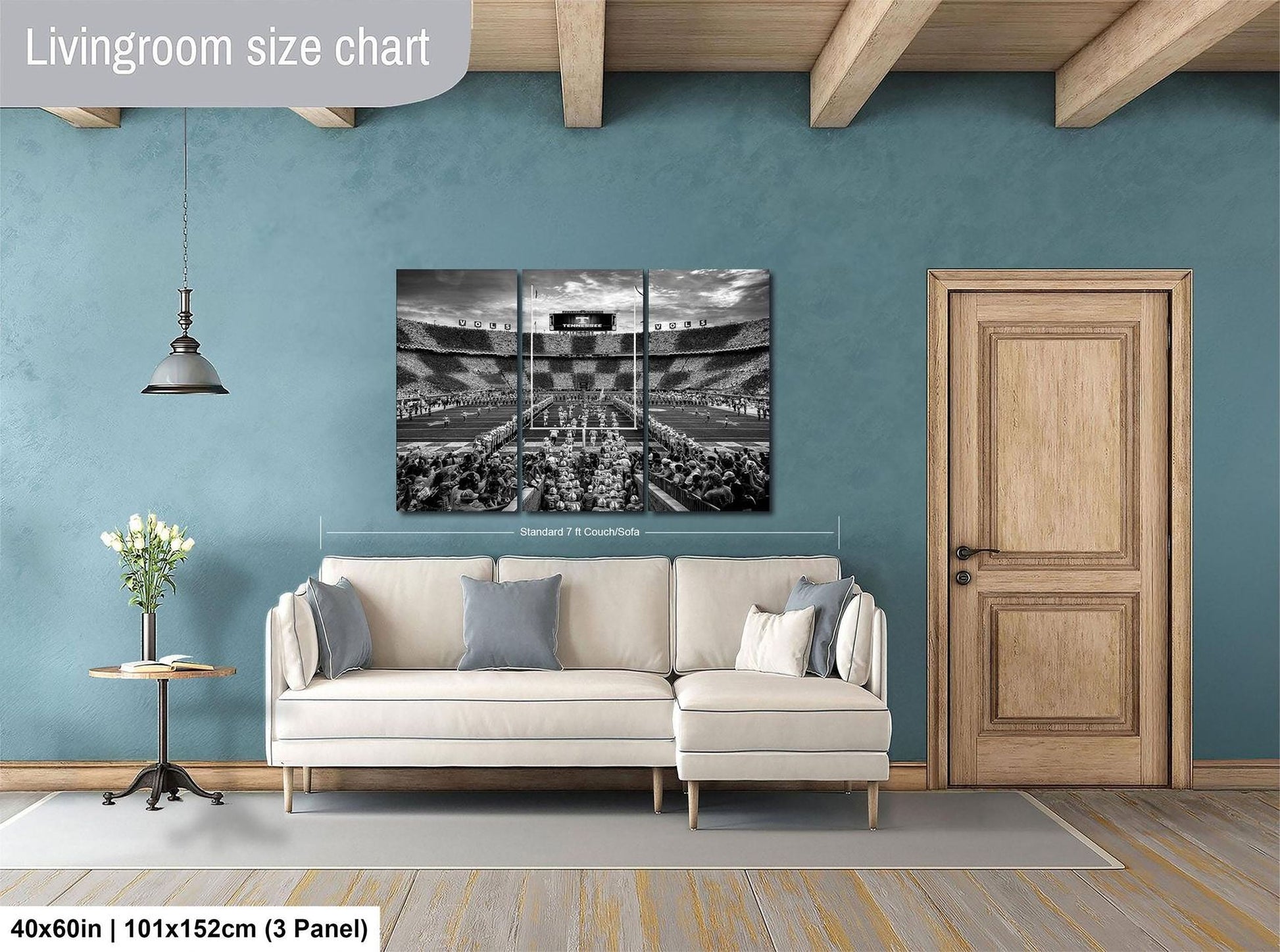 a living room with a large black and white photograph of a stadium or arena displayed on the wall. The room has a white sofa, a wooden door, and a wooden floor.