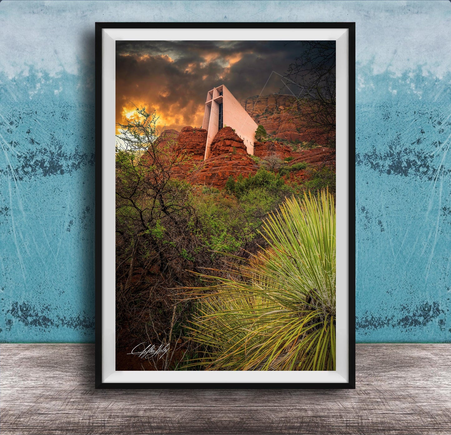 a framed photograph of a desert landscape with a large, white structure in the background, possibly a building or monument, set against a dramatic sky with clouds and a sunset.