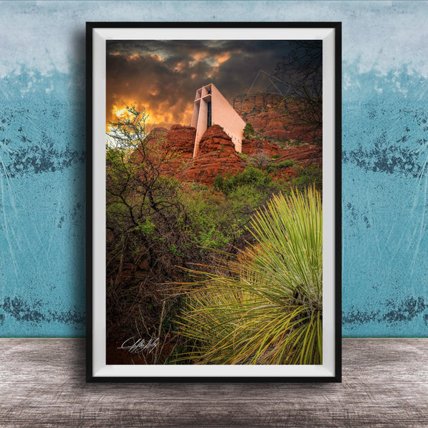 a framed photograph of a desert landscape with a large, white structure in the background, possibly a building or monument, set against a dramatic sky with clouds and a sunset.