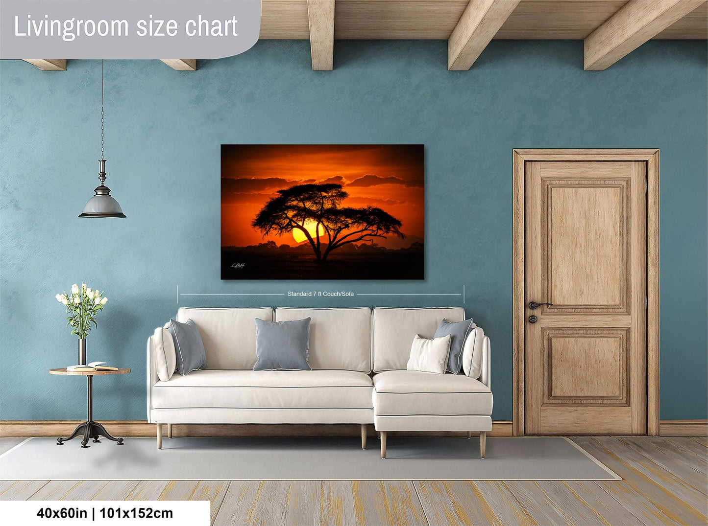 a living room with a large white sofa, a wooden door, and a painting of a tree with a sunset in the background.