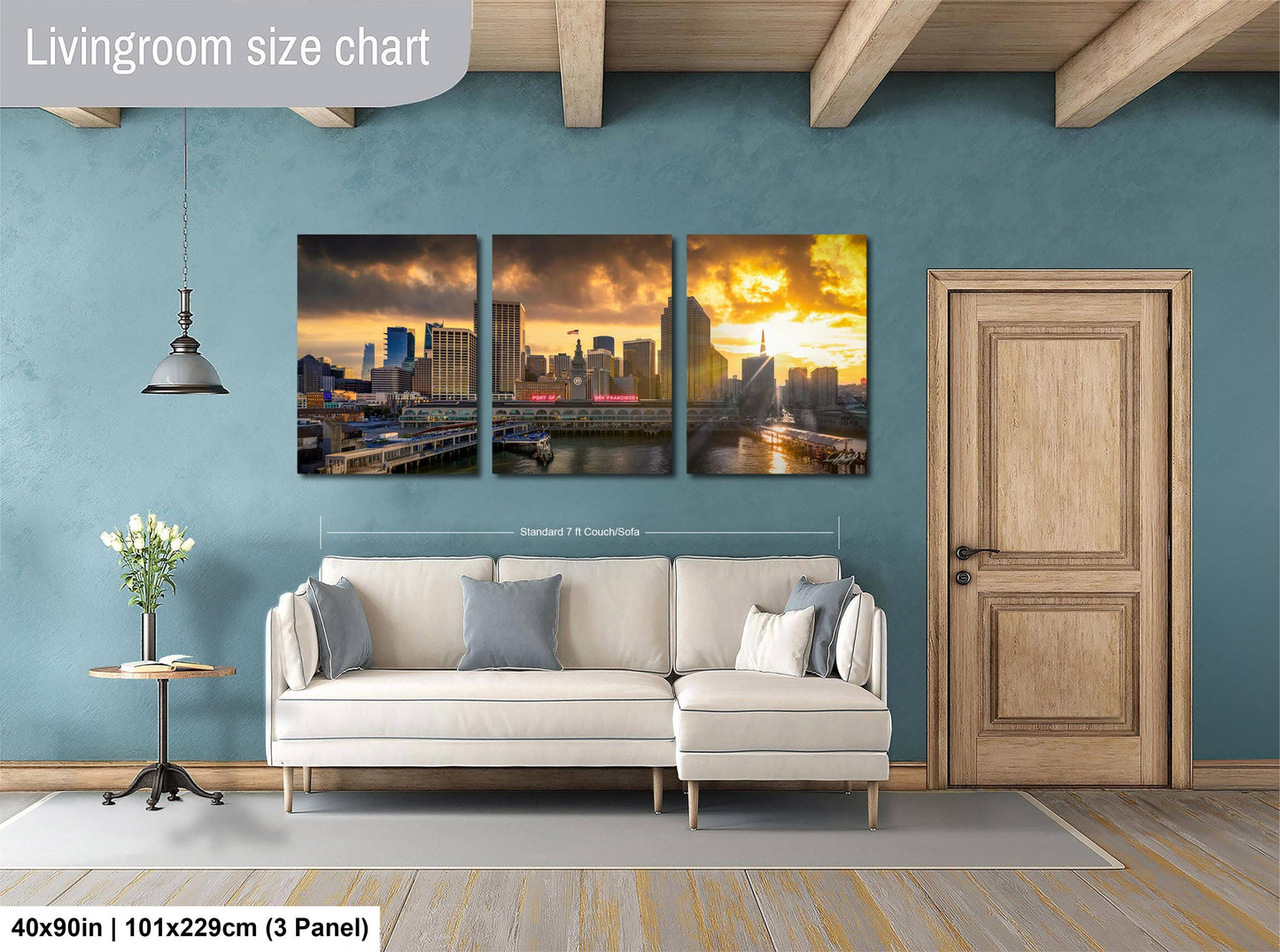 The image is a living room with a large wall art collage depicting a city skyline at sunset. The collage consists of three panels, each showing a different view of the cityscape. The collage is framed by a wooden door and a white sofa, creating a cozy and inviting atmosphere. The wall art is approximately 40 inches wide and 101.29 cm tall, with a 3-panel arrangement.