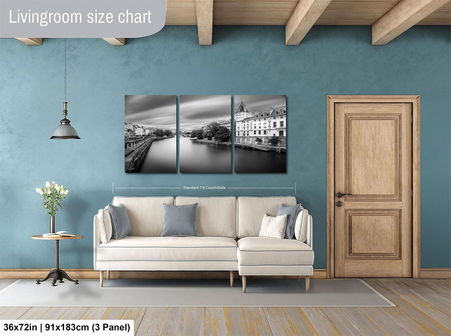 The image is a living room with a large wall art piece depicting a cityscape. The art piece is divided into three panels, each showing a different part of the city. The living room has a white sofa and a wooden door, and the floor is covered with a gray rug.